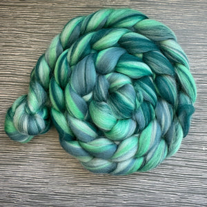 Braided skein of green yarn on a wooden surface