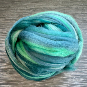 Bundle of green and blue yarn on a wooden surface