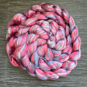 Braid of pink and gray fiber on a wooden surface